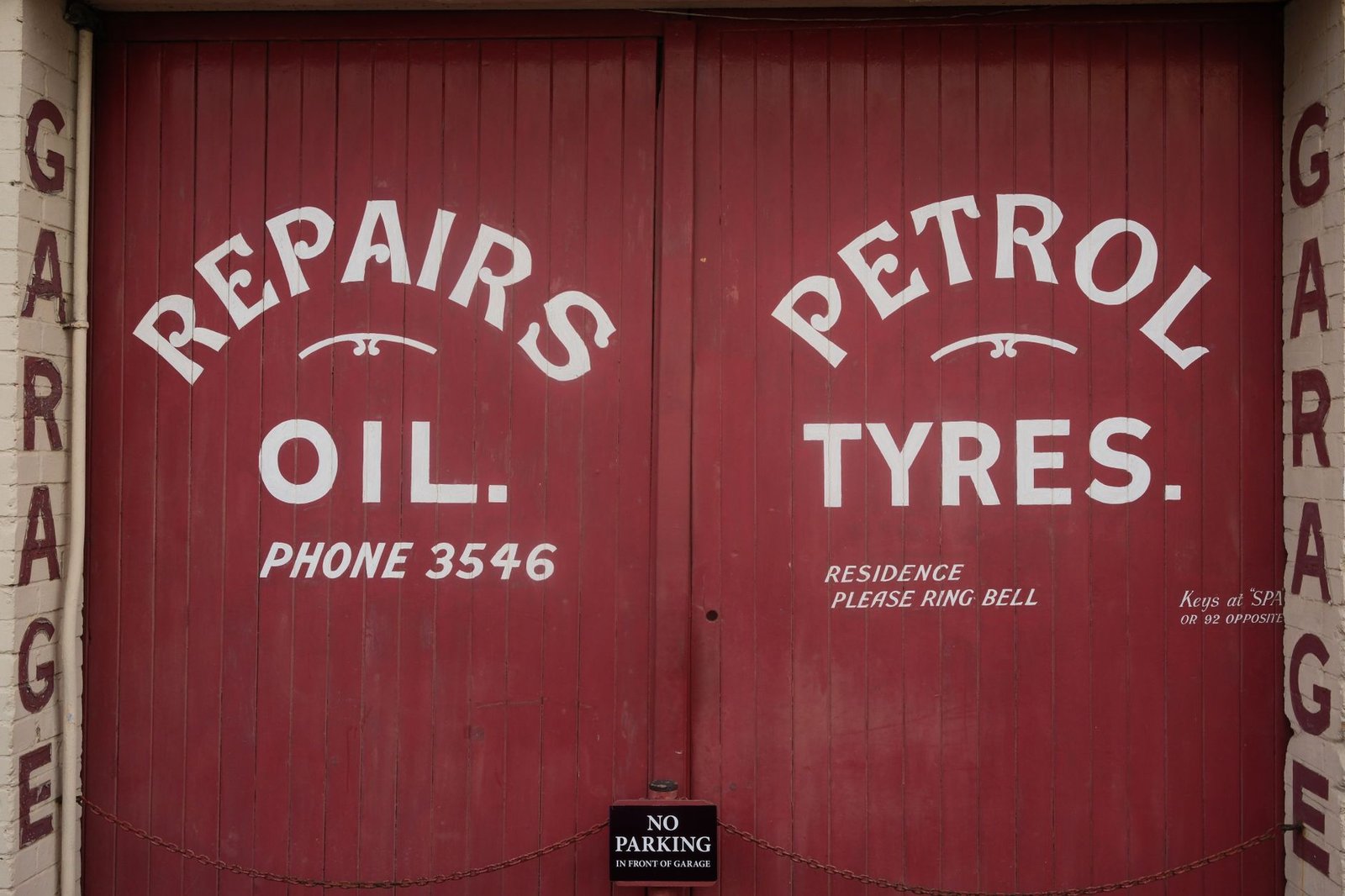 Red garage doors with retro-style signage for repairs and petrol in Bristol, UK.