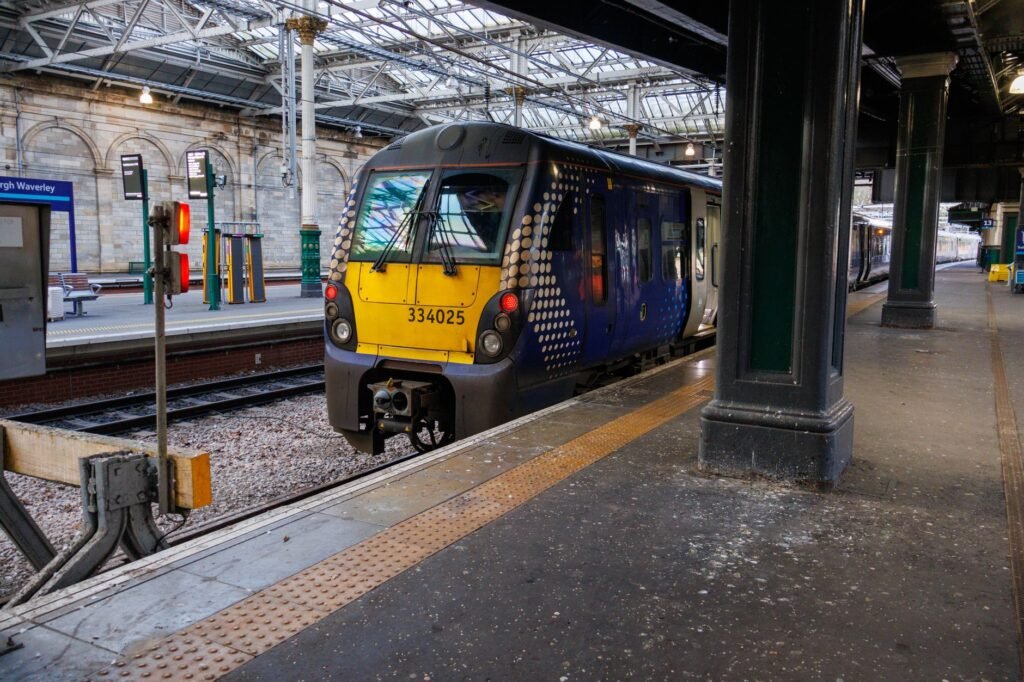 A modern train parked at Edinburgh Waverley Station platform, Scotland.