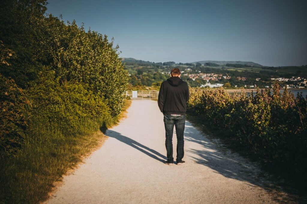 A lone man walks on a picturesque outdoor path surrounded by nature.