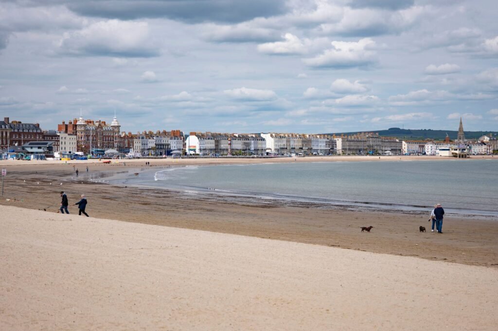 Serene beach scene at Weymouth with people strolling along the sand and vibrant sea views.
