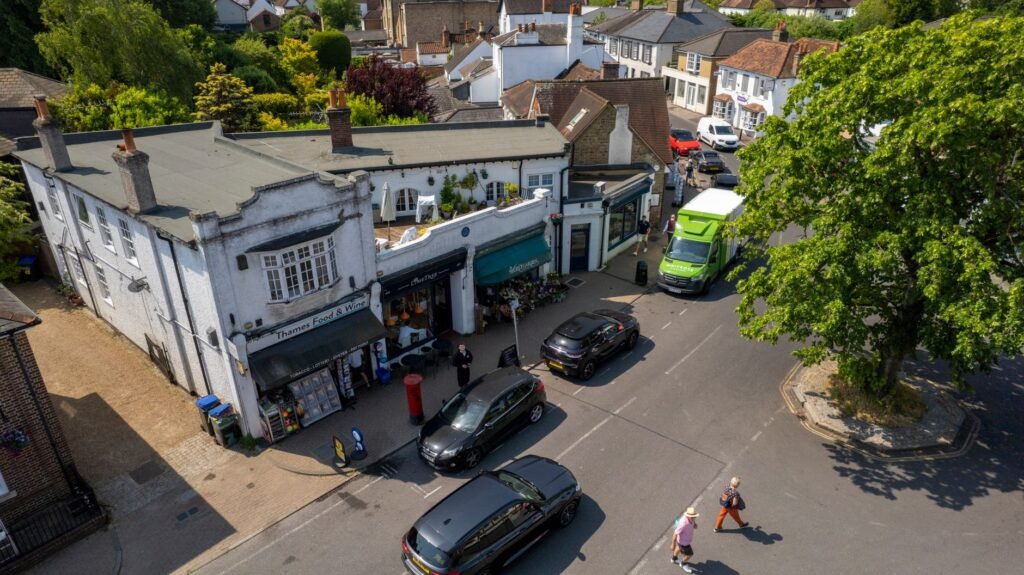 A sunny aerial capture of a bustling street in Thames Ditton, showcasing shops and a busy intersection.