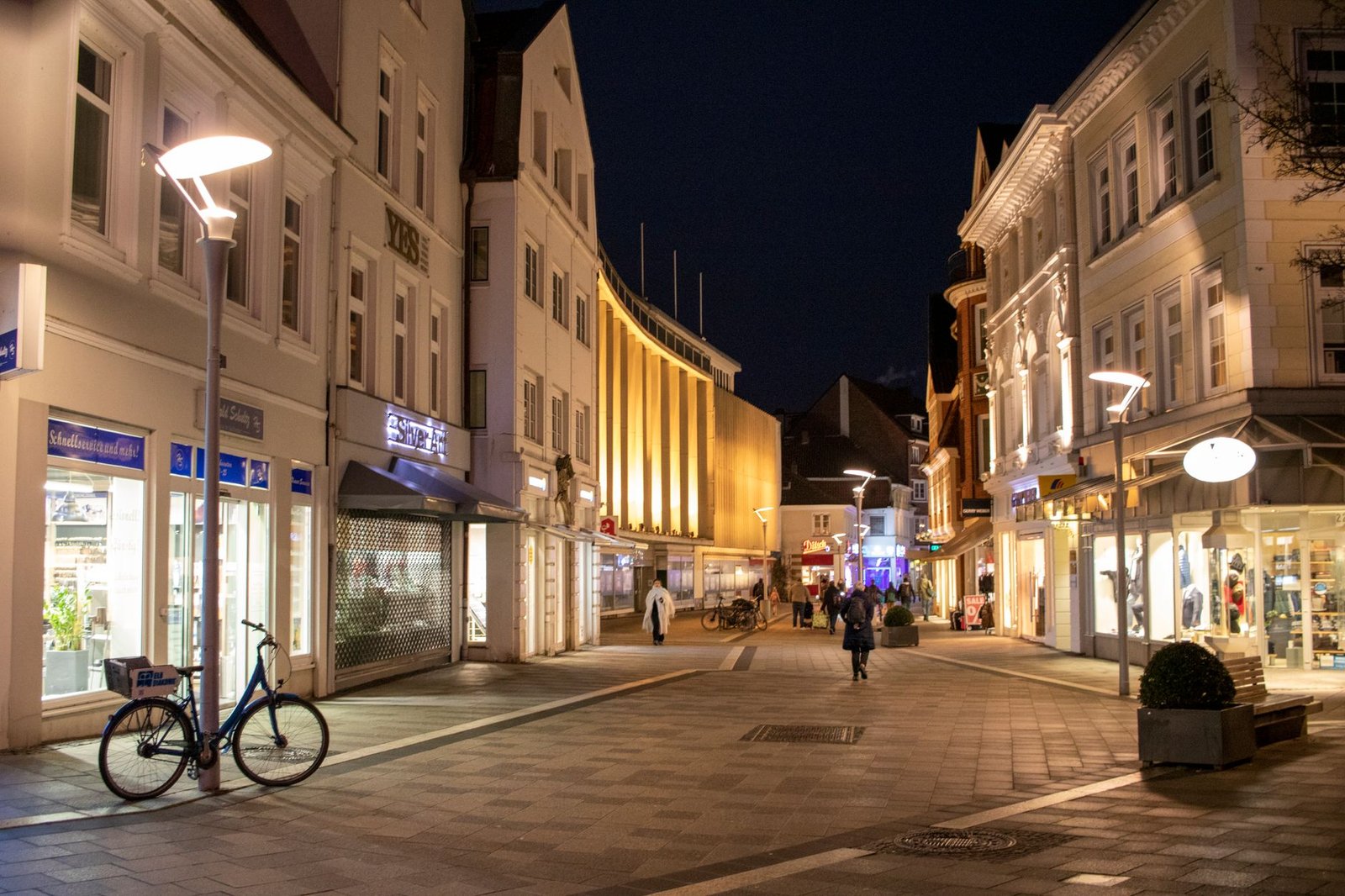 Night view of a vibrant street in Hamburg with illuminated buildings and people strolling.