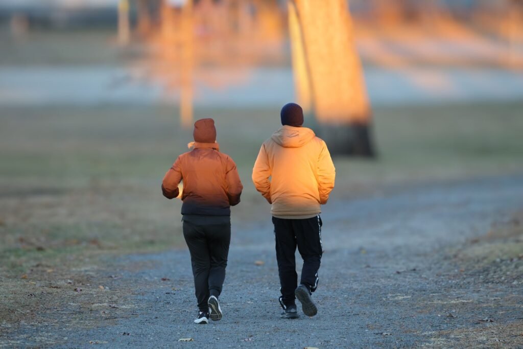 Two adults walking in autumn at dawn in Stamford, capturing the tranquility of the morning light.