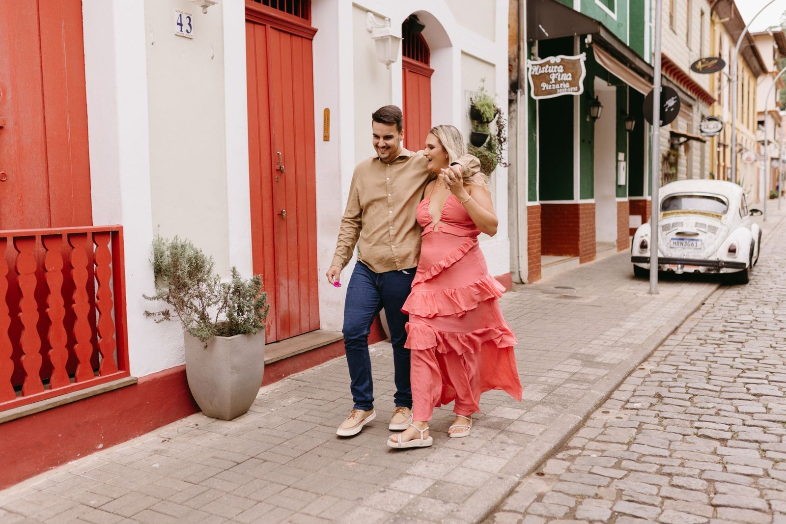 A cheerful couple walking on a vibrant, historic city street enjoying a sunny day.