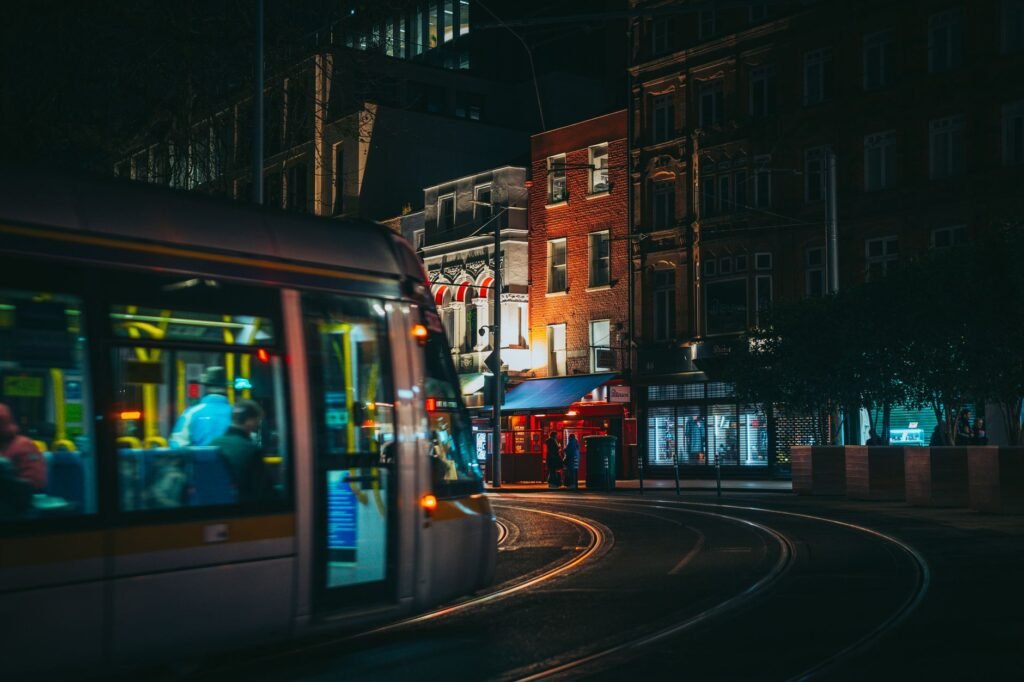 Dynamic city night scene with a moving tram passing illuminated shops.