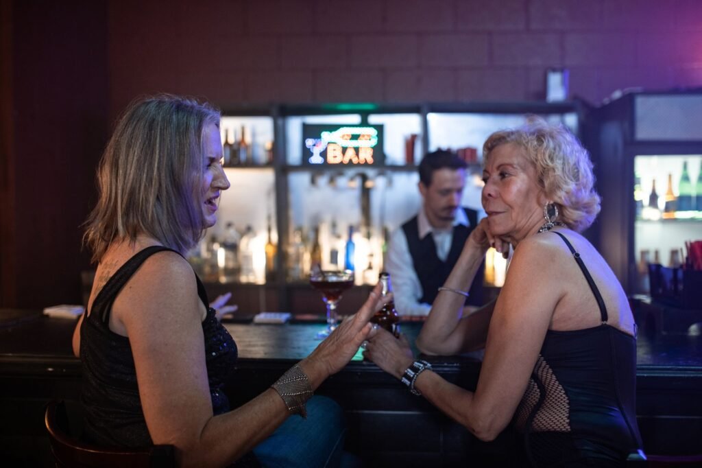 Two women enjoying conversations and cocktails at a stylish bar during a lively night out.
