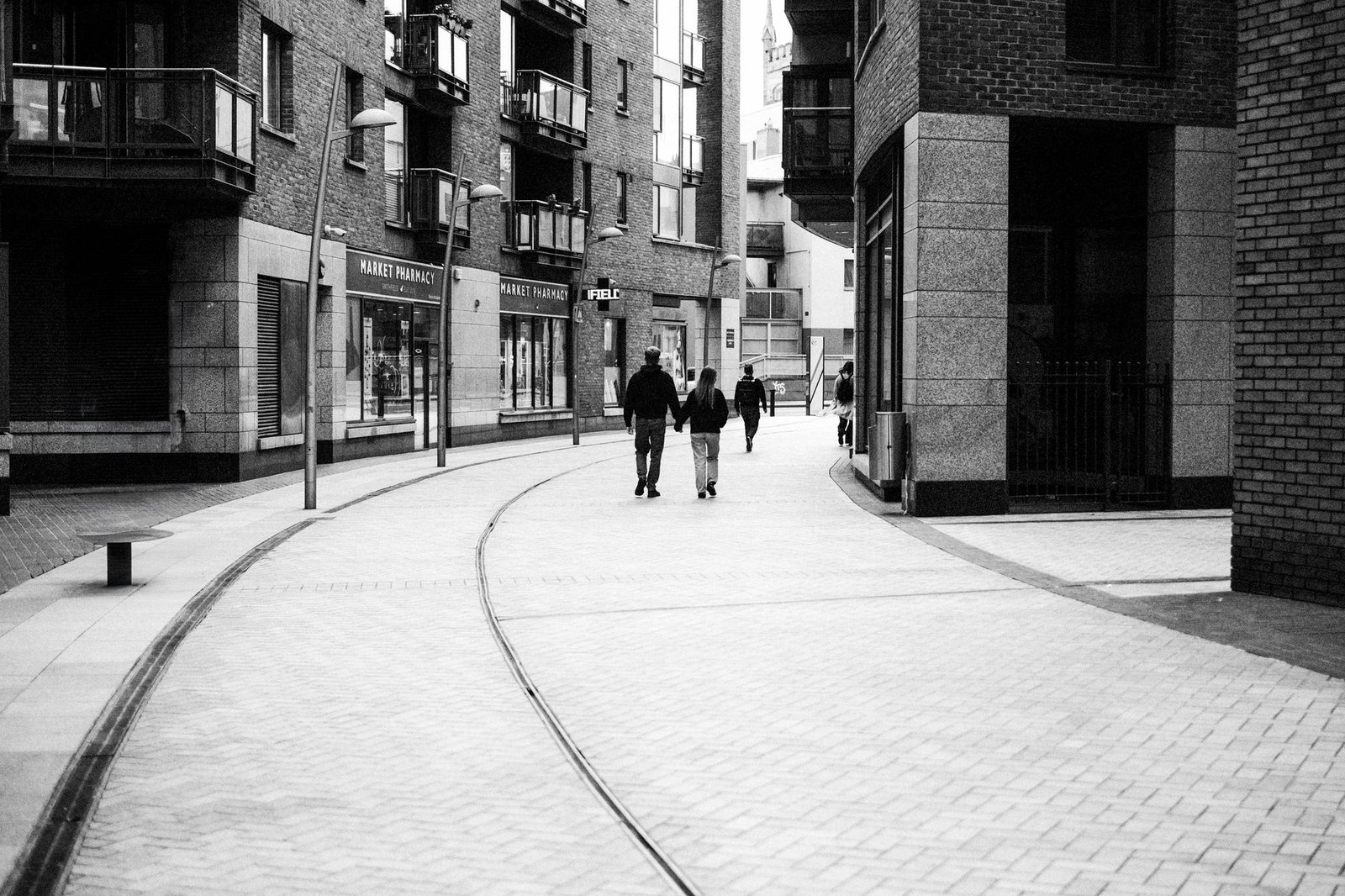 Urban street in Dublin with people walking, showcasing modern architecture in a monochrome setting.
