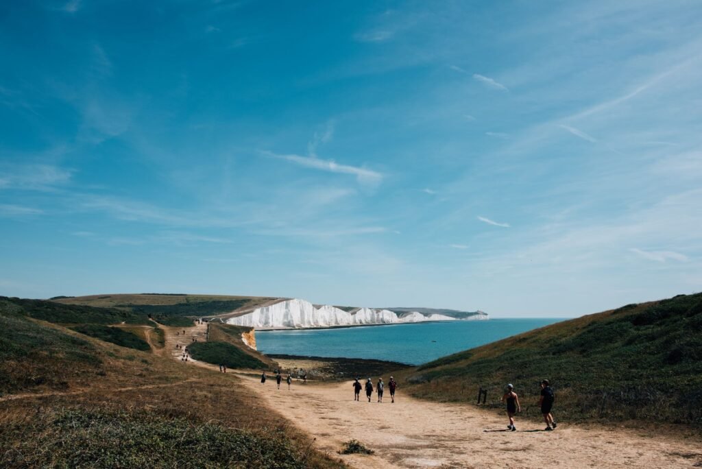 Explore the stunning landscape of Seven Sisters Cliffs with people enjoying a sunny day hike by the sea.