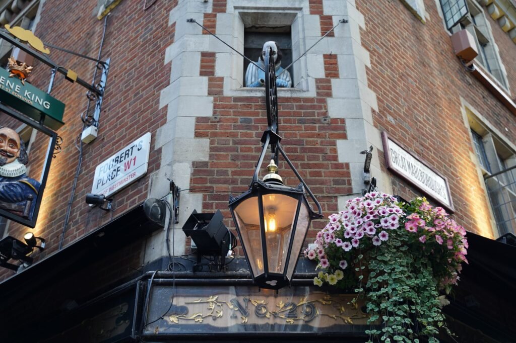 Charming urban facade featuring a classic street lamp, brick wall, and blooming flowers.