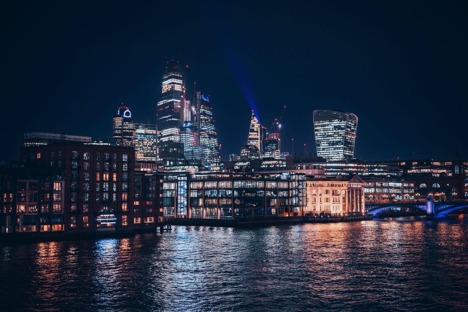 Captivating view of London's skyline at night, showcasing modern architecture and riverside reflections.