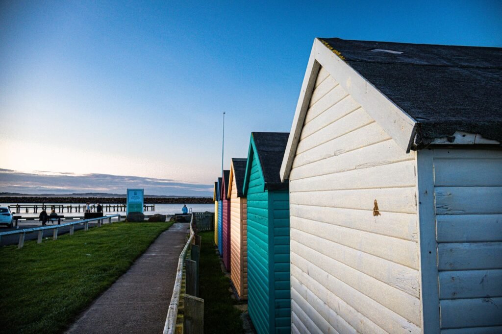 Vibrant beach huts lined along a serene coastline during sunset, offering a picturesque view.