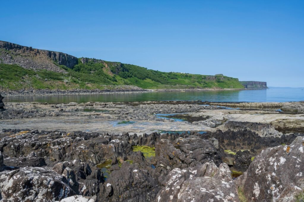 Explore the rugged rocky shoreline of Scotland's stunning coastline under a clear blue sky.