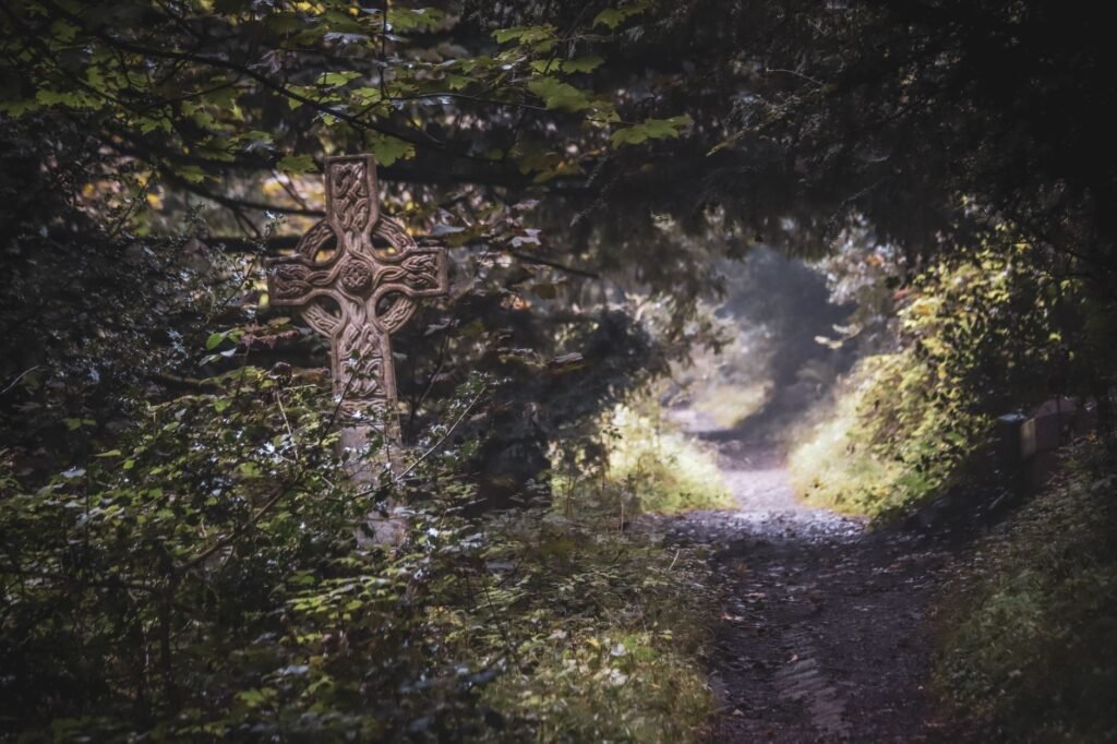 A scenic view of a Celtic cross amidst lush greenery along a forest trail in Bristol, England.