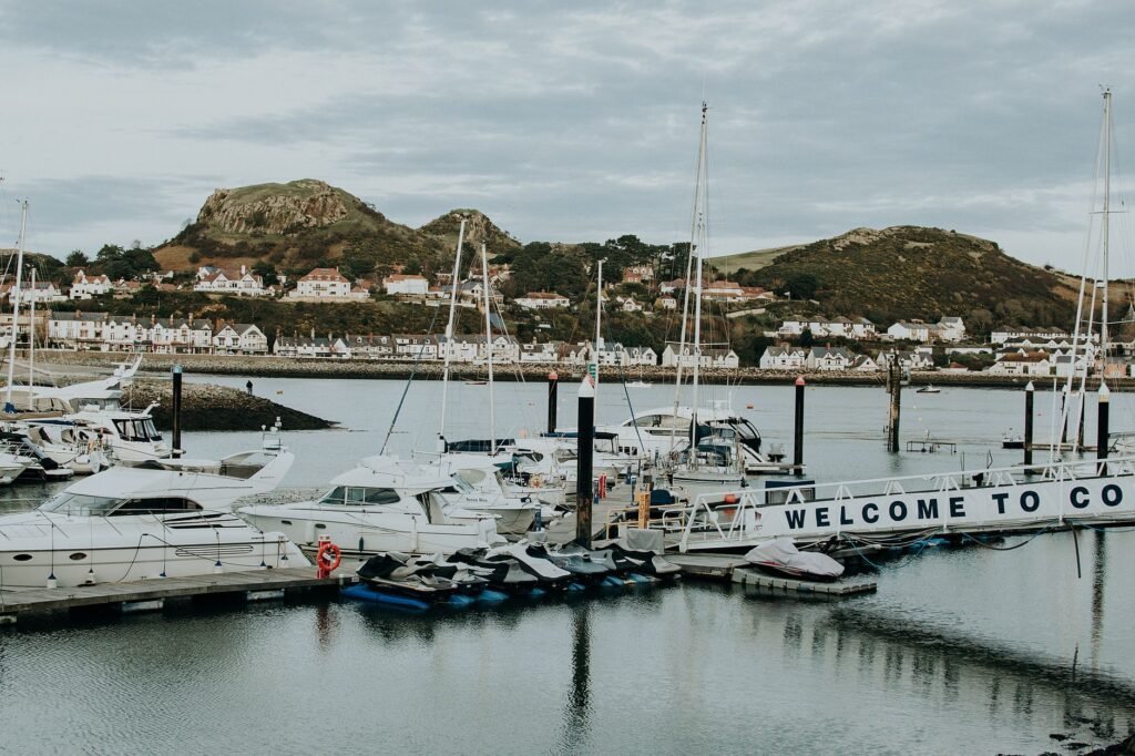 Yachts moored at a picturesque marina with hilly backdrop in a tranquil coastal town, perfect for travel and marine themes.