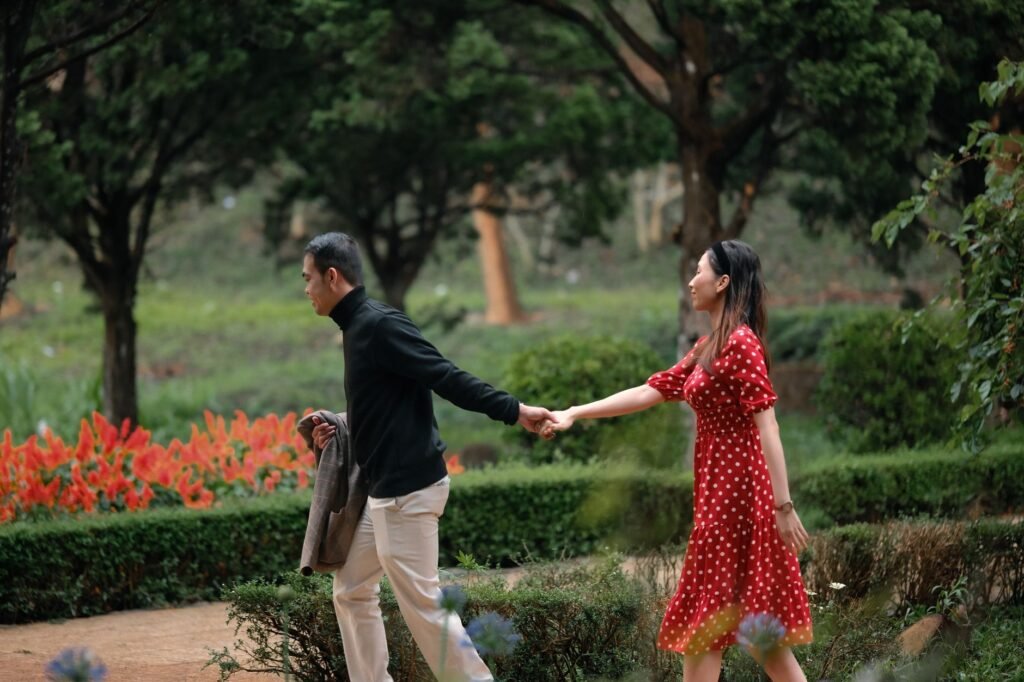 Couple holding hands walking through a picturesque garden, showcasing love and serenity.