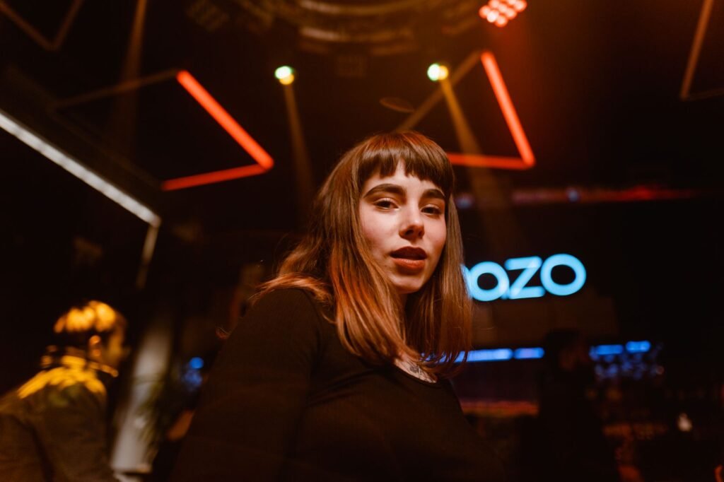 Woman with bangs enjoying a lively night out in a vibrant, modern nightclub.