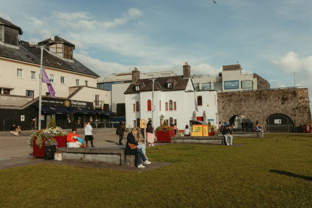 Lively scene at Spanish Arch, Galway, Ireland with people and historic buildings.