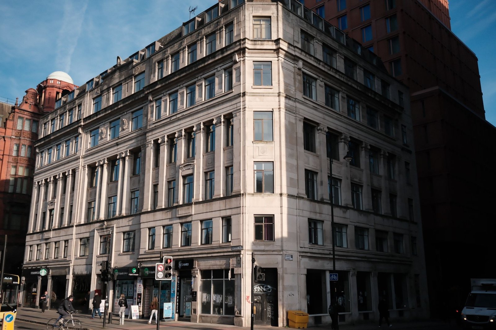 Classic architecture of a historic building on a busy city street corner, bathed in sunlight.