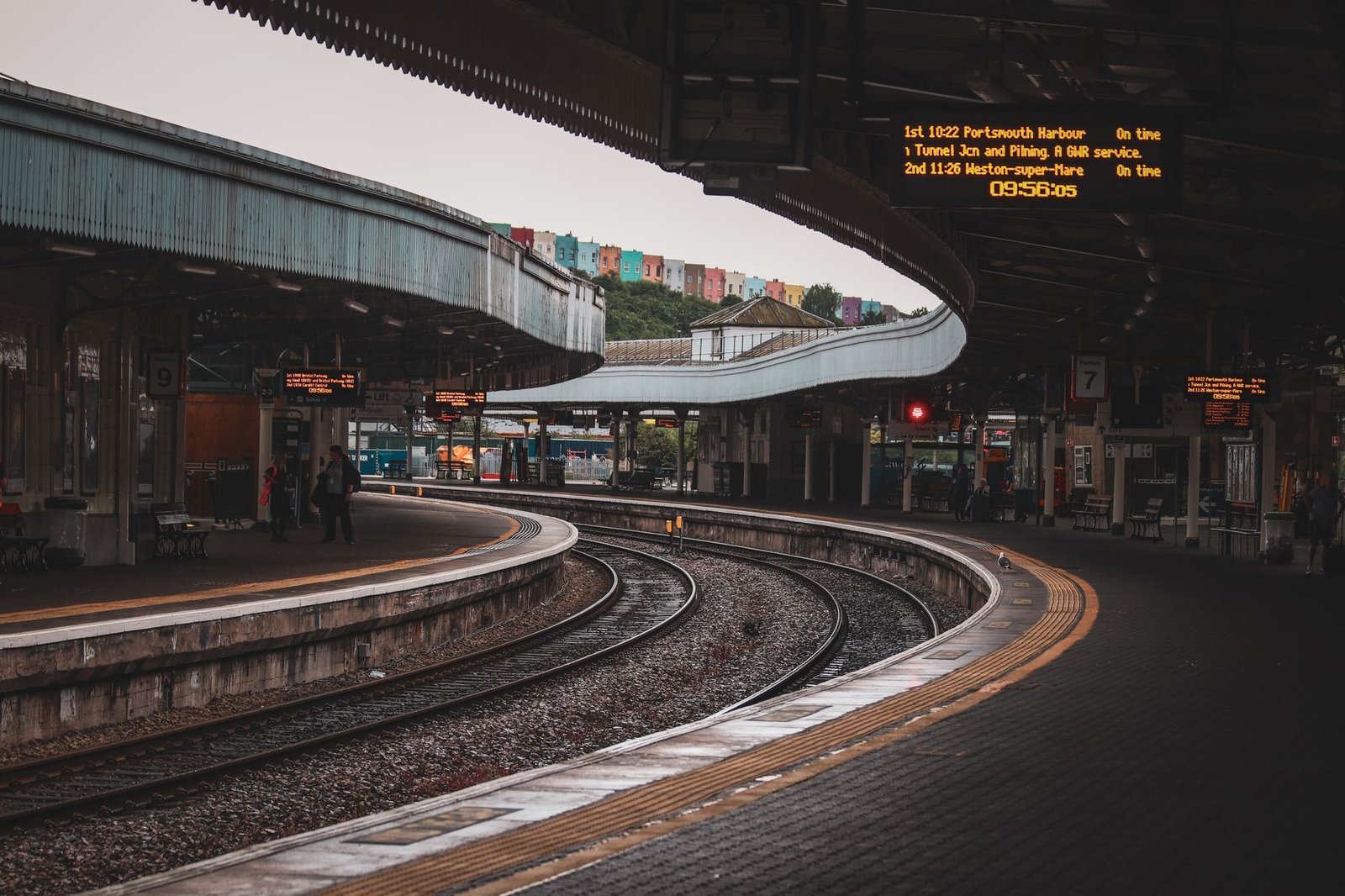 Urban train station with curved tracks and platform, featuring modern architecture.