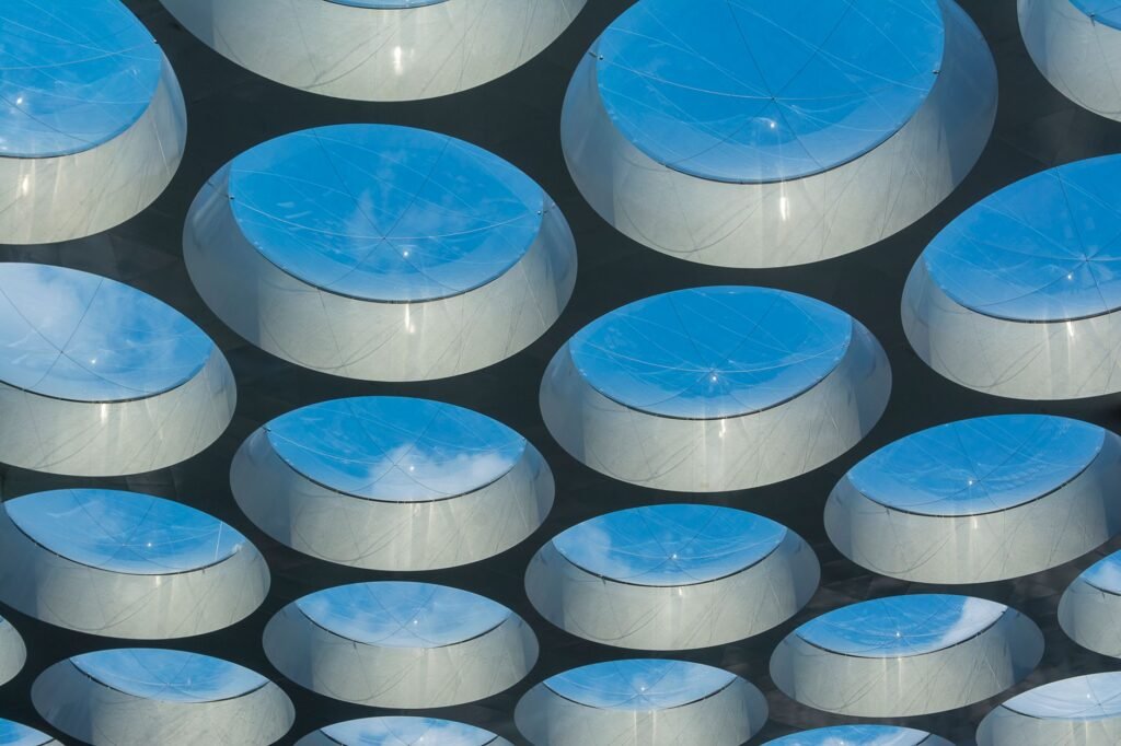 Geometric glass ceiling featuring reflective domes with sky reflections, capturing modern architecture.