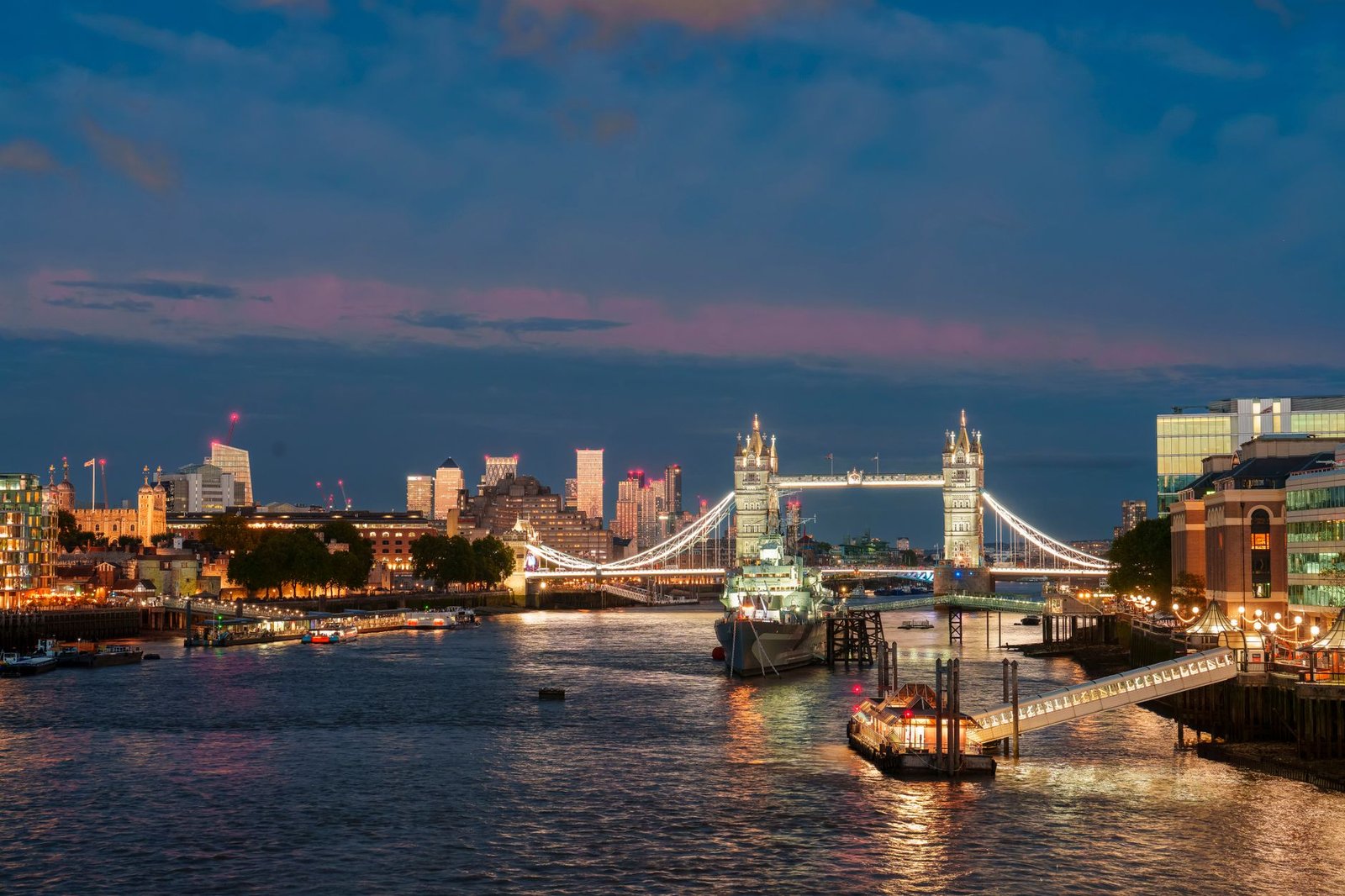 Stunning night view of Tower Bridge illuminated over the River Thames in London, showcasing the city's skyline.