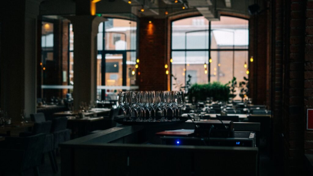 A dimly lit restaurant interior featuring a set of clean wine glasses and a cozy atmosphere.