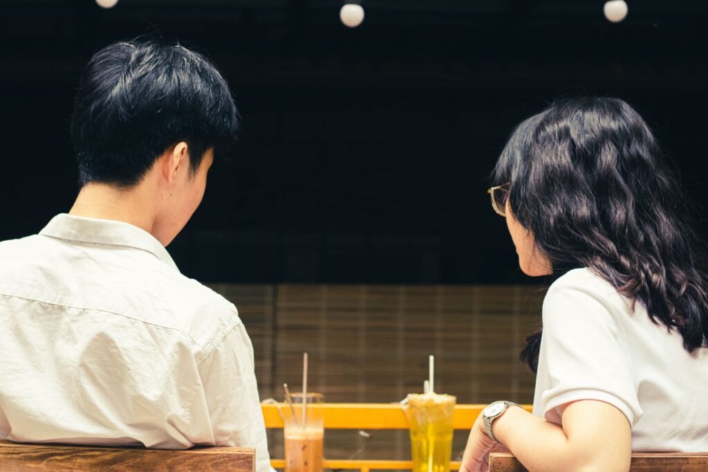 Young couple enjoying refreshing drinks while seated outdoors at a cafe, creating a relaxed atmosphere.
