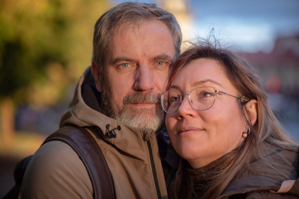 A close-up portrait of a smiling couple enjoying a sunny day outdoors.