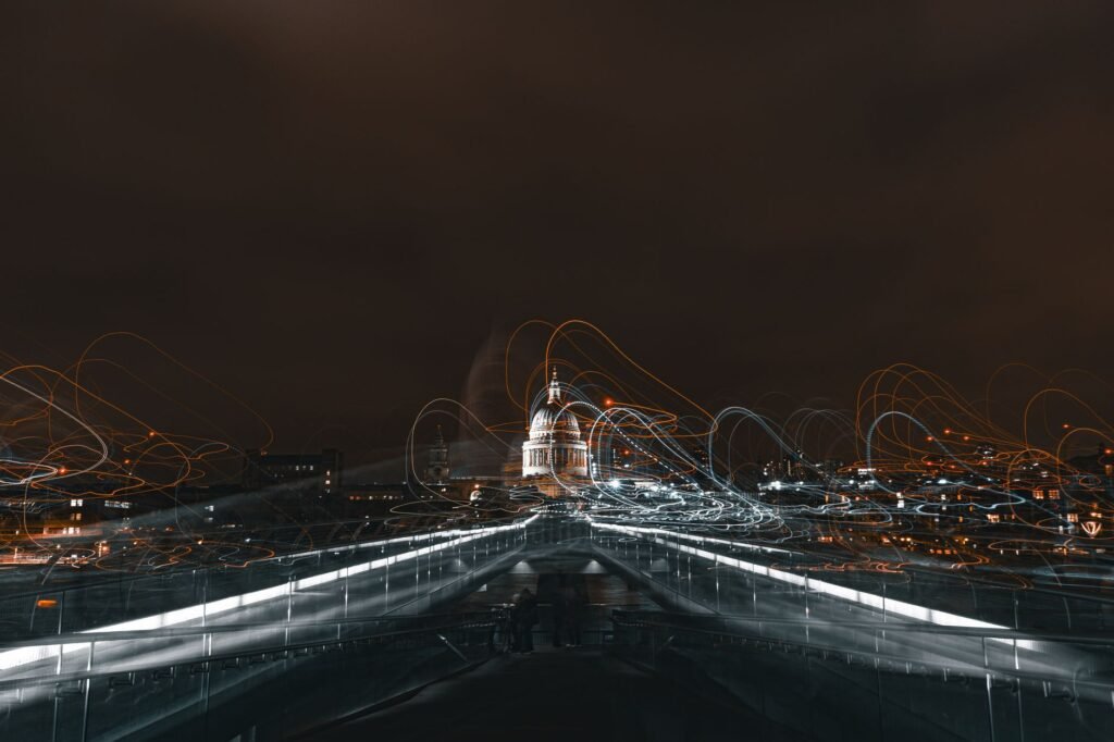 Dynamic night shot of Millennium Bridge with light trails leading to St Paul's Cathedral in London.