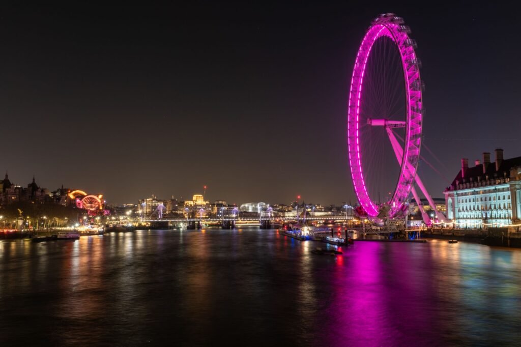 Experience the vibrant London Eye at night with dazzling city lights reflecting on the Thames.