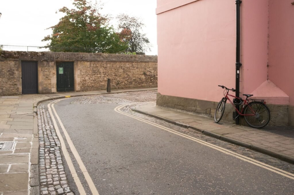 Quiet Oxford street scene featuring a vintage bicycle against a pink wall.