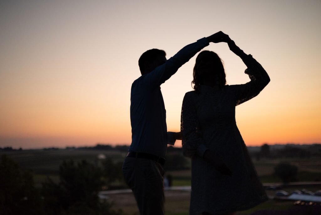 A romantic silhouette of a couple dancing outdoors against a vibrant sunset in Kraków.