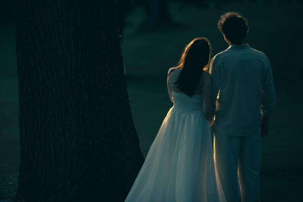 A couple stands together under twilight, creating a dreamy, romantic scene.