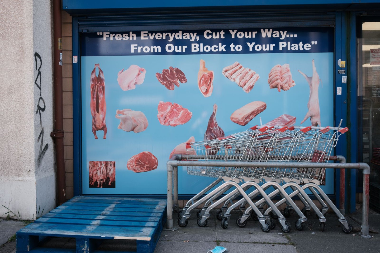 Butcher shopfront advertising meats with shopping trolleys in Swindon, UK.