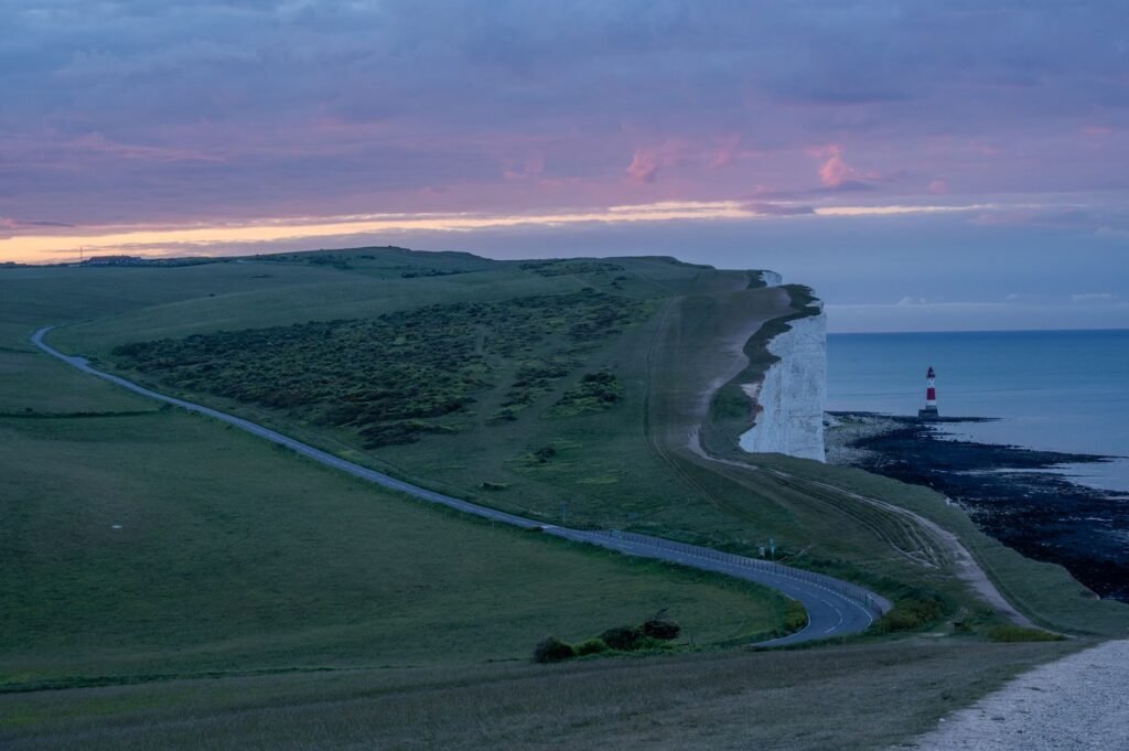 A breathtaking view of Beachy Head cliffs at sunset with a distant lighthouse