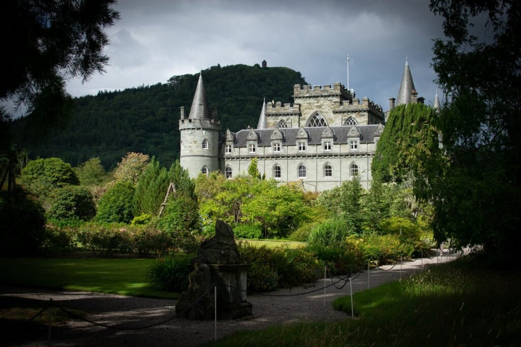 Inveraray Castle surrounded by vibrant gardens and lush greenery under cloudy skies in Scotland.