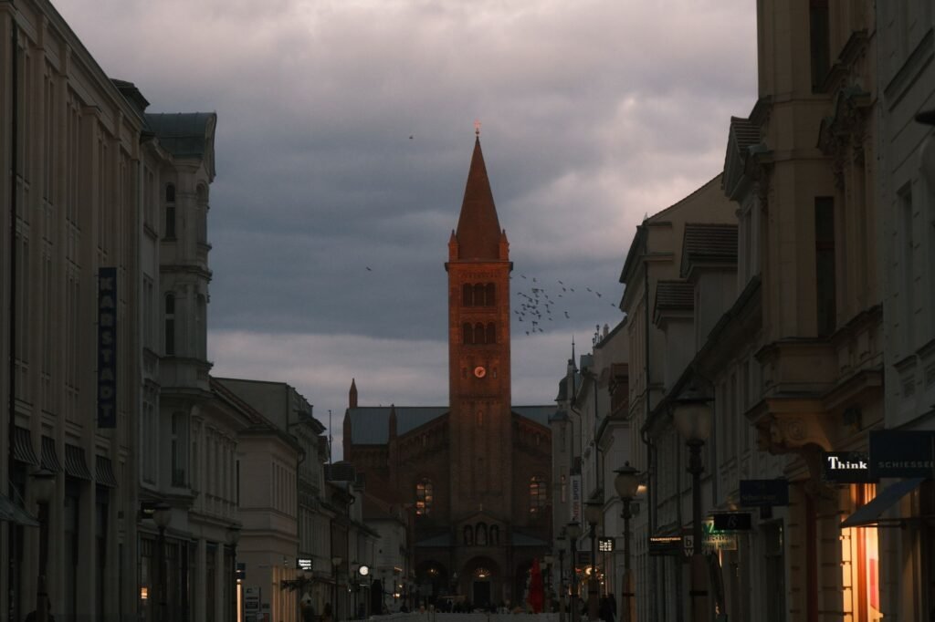 View of a Gothic-style church tower during dawn in Potsdam, surrounded by historic architectural buildings.