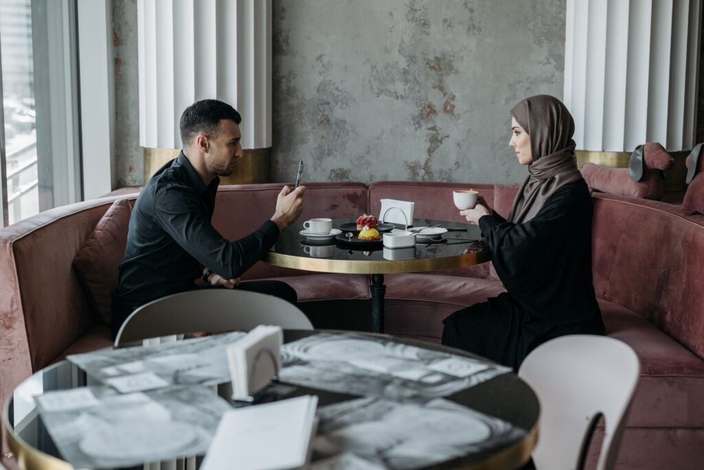 A Muslim couple sharing a peaceful breakfast at a cozy indoor cafe setting.
