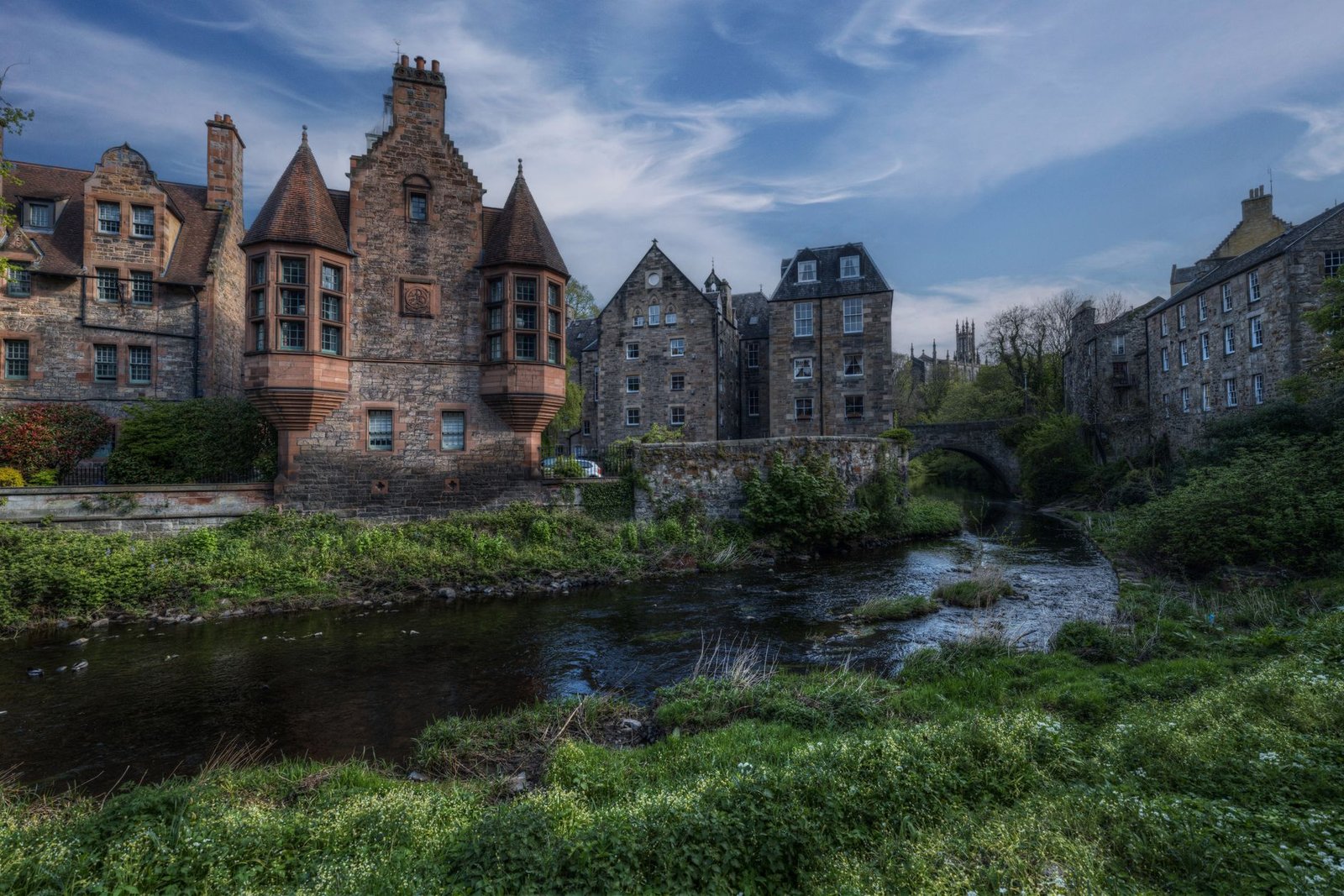 Charming stone buildings along a peaceful river in Edinburgh, showcasing historic architecture.