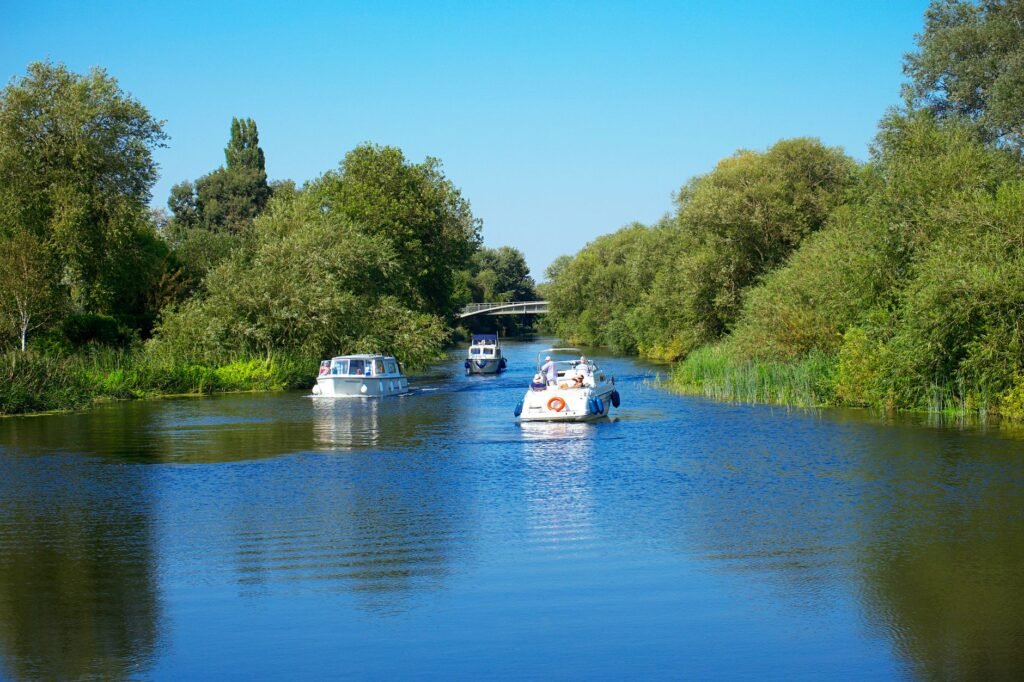 Idyllic view of boats cruising on a river surrounded by lush greenery in St Neots, England.