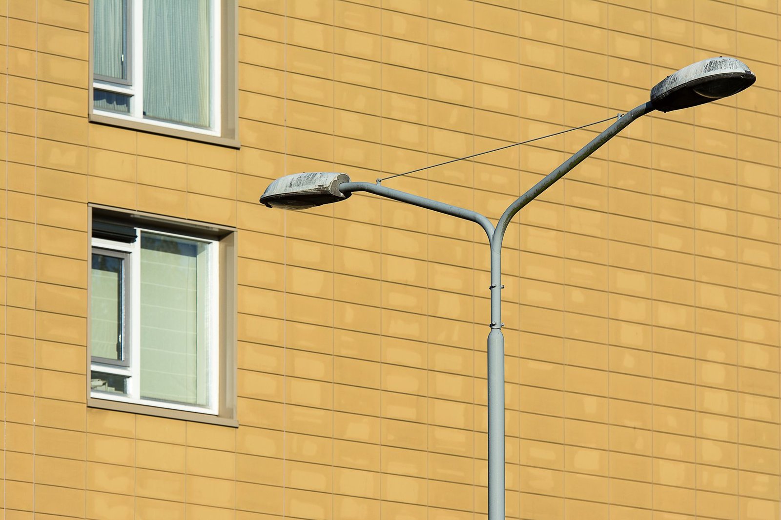 A street lamp in front of a yellow building with windows, showcasing urban architecture.
