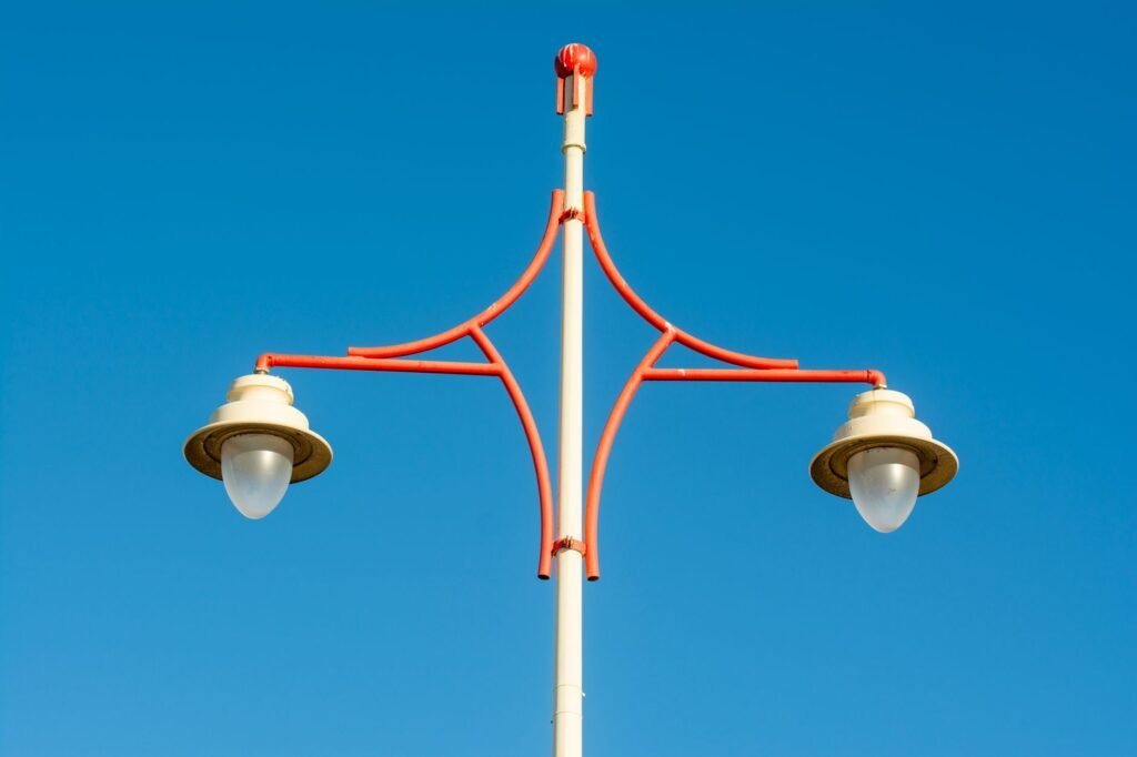 Bright red vintage streetlamp against a cloudless blue sky provides a striking urban aesthetic.