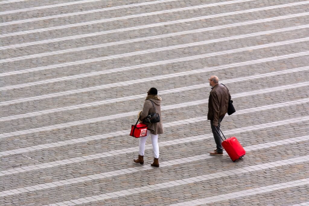 Aerial view of people walking with luggage on a patterned pavement, showcasing urban travel.