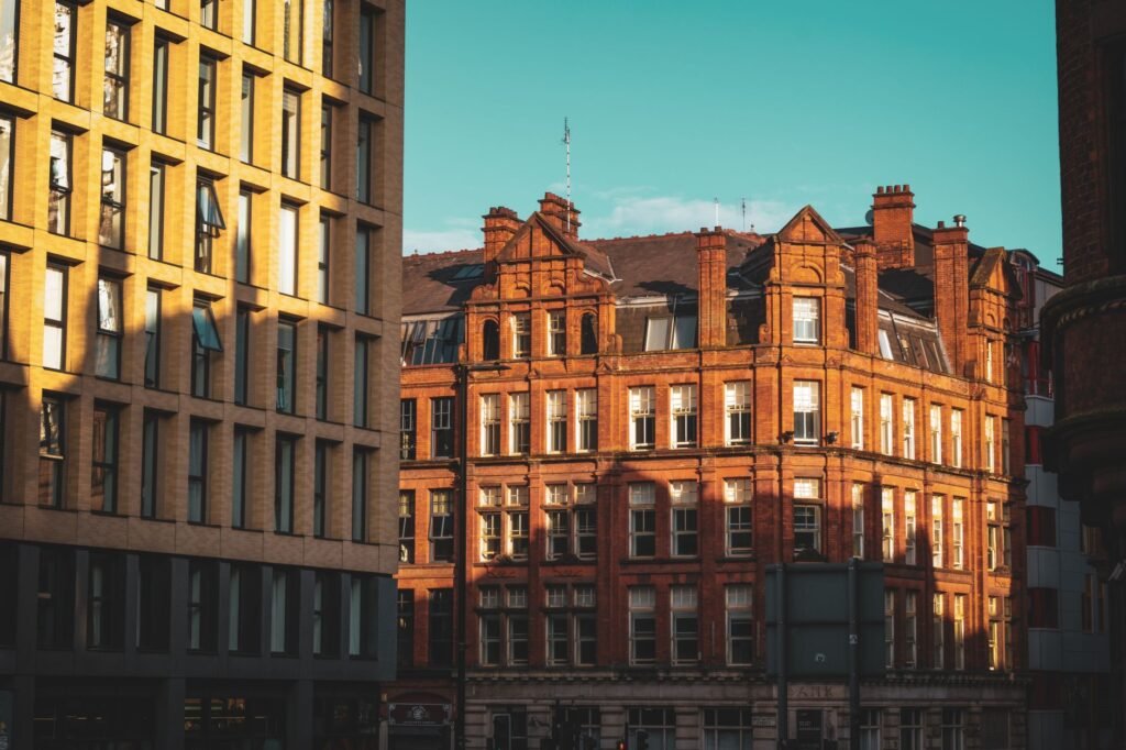 Sunlit red brick building amidst modern structures in a vibrant city street.