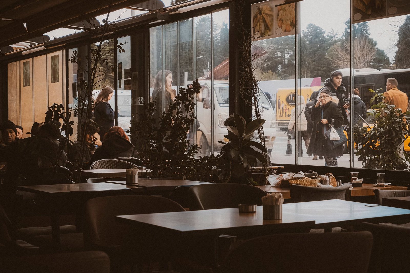 Warm interior of an Istanbul cafe with street view and pedestrians passing by.