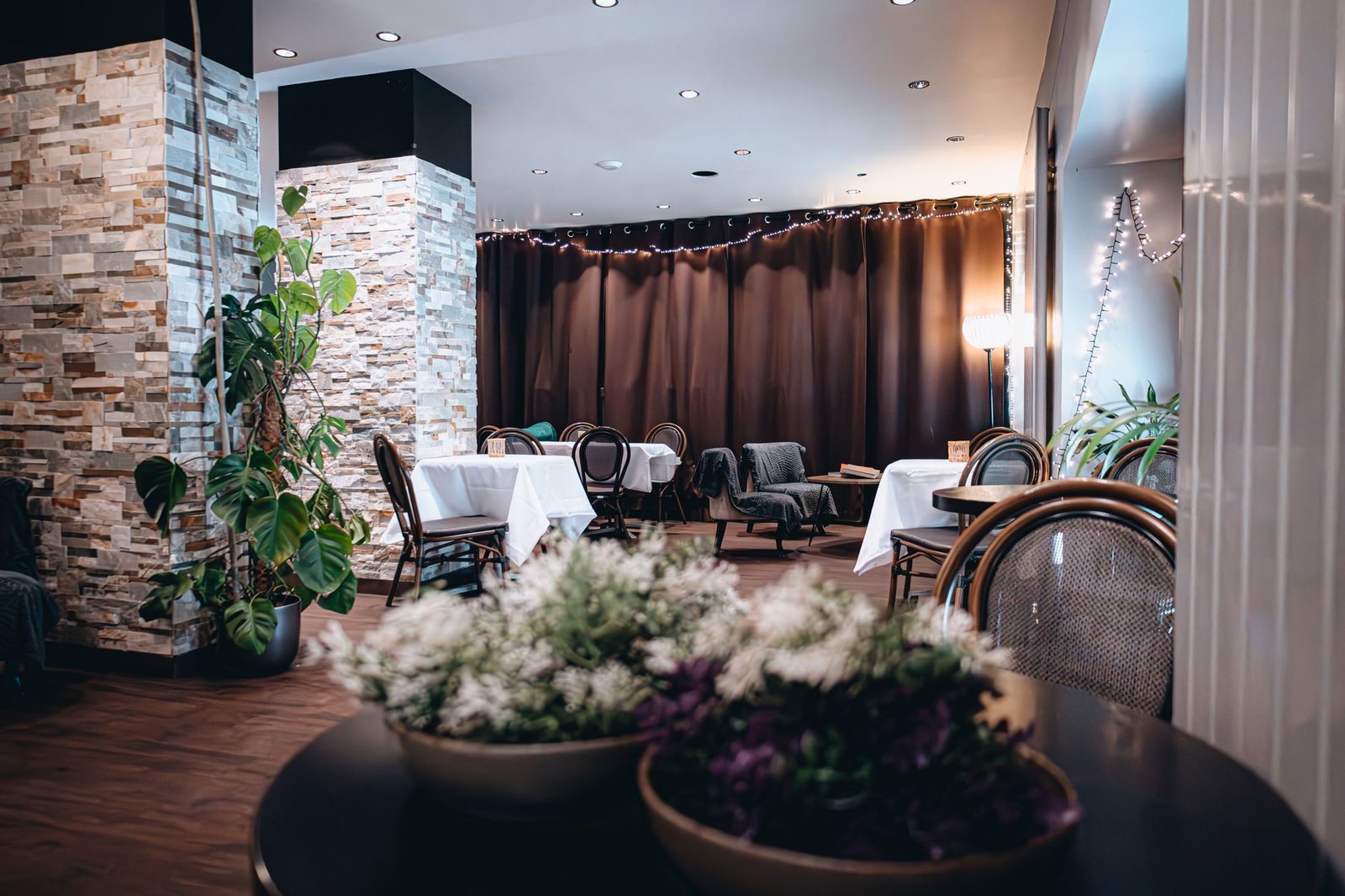 Chic cafe interior featuring cozy tables, stylish lighting, and elegant plant decor, perfect for leisure and relaxation.