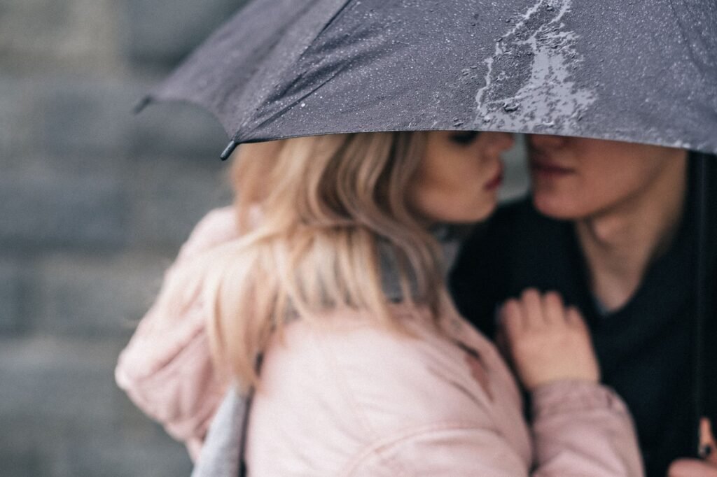 Close-up of a couple sharing a romantic moment under an umbrella on a rainy day.