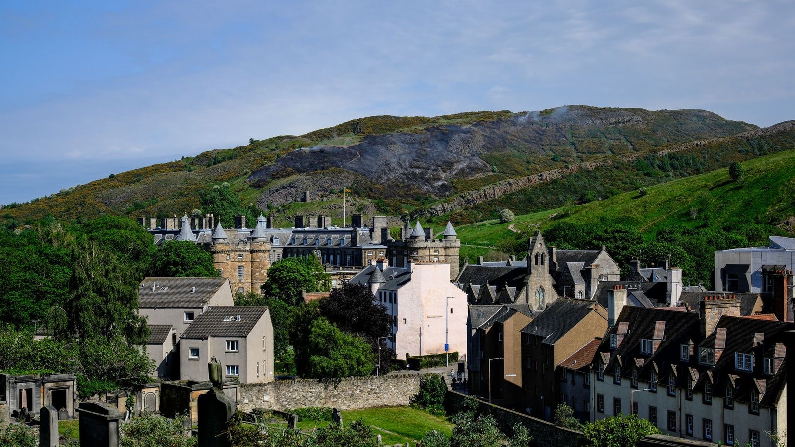 Charming view of Edinburgh's historic architecture with Arthur's Seat in the background on a sunny day.