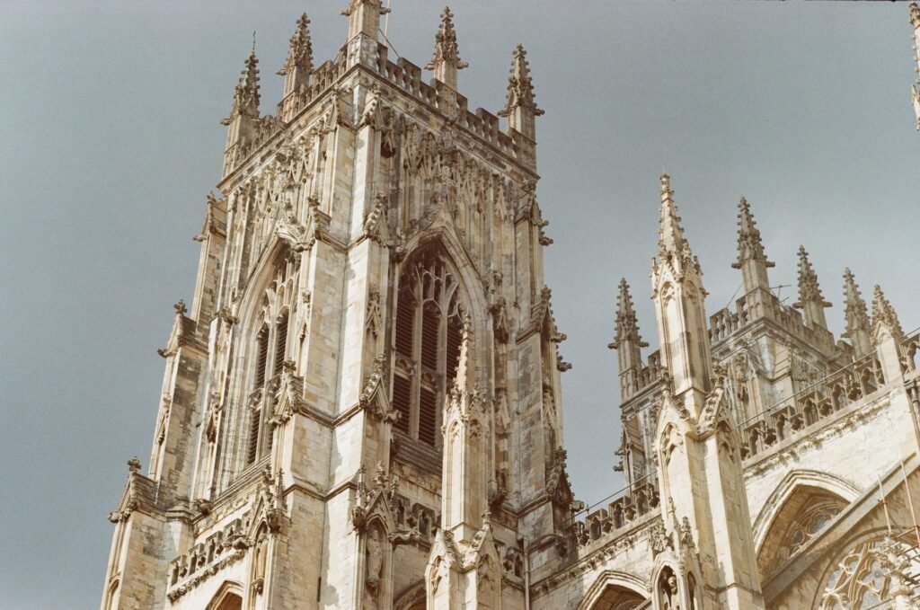 Close-up of York Minster's stunning gothic spires and intricate architecture under a cloudy sky.