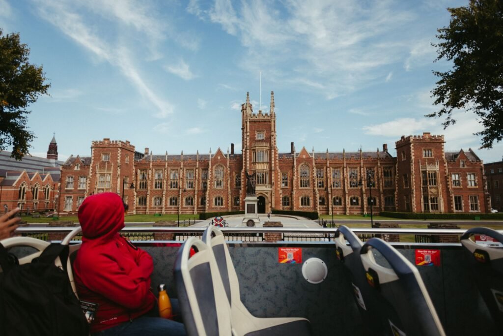 View of Queen's University Belfast captured from a tourist bus, showcasing stunning Gothic architecture and vibrant campus li